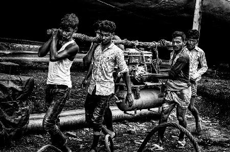 Carrying a motor in a shipyard in Bangladesh.