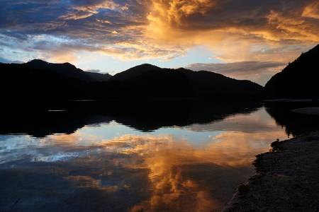 Romantisches Abendrot mit Wolkenstimmung und Bergsilhouette am Almsee