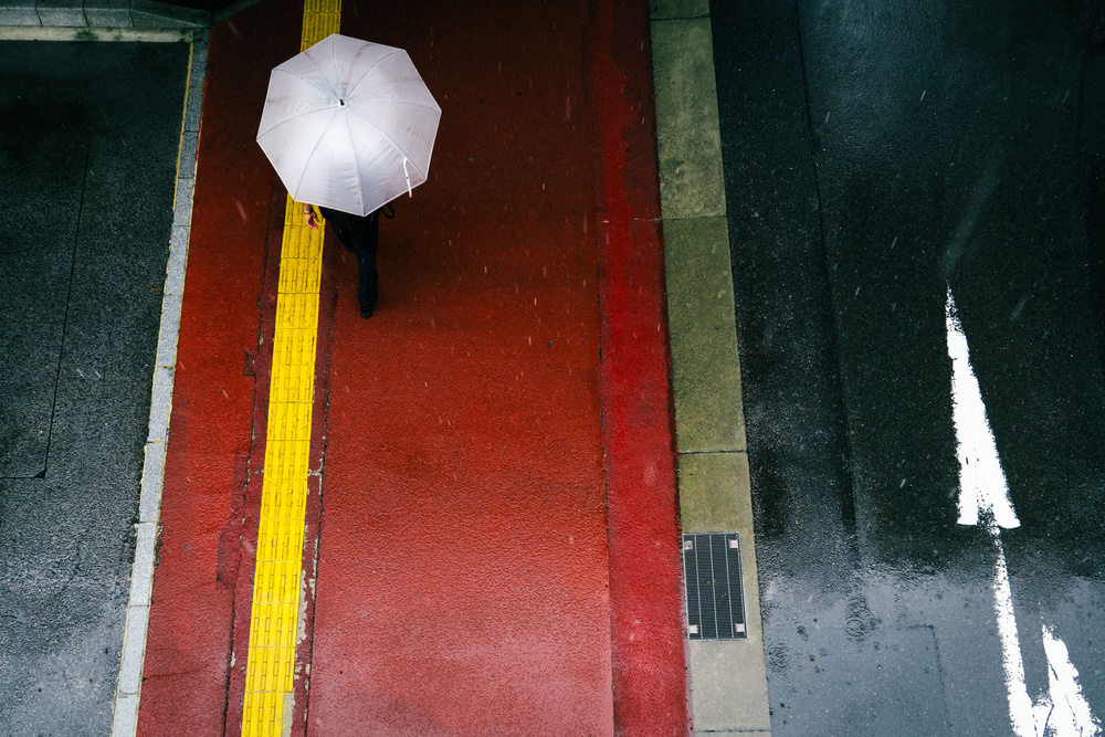 The red sidewalk and a white umbrella od Tetsuya Hashimoto